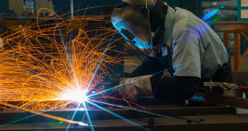 Welder uses torch to make sparks during manufacture of metal equipment.